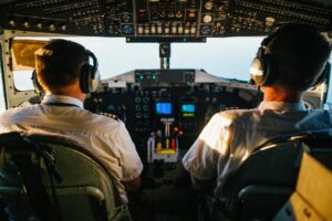 Dos pilotos en la cabina de un avión, observando el panel de control durante el vuelo